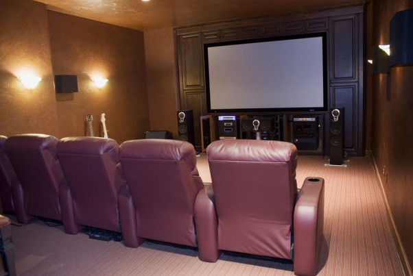Home theater setup featuring leather recliners, large screen, audio equipment, and ambient lighting for professional LCD or Plasma TV installation.
