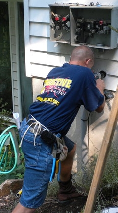 Electrician working on a residential electrical panel, demonstrating professional electrical services for safe installations and repairs.