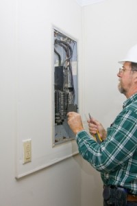Electrician inspecting circuit breaker panel, troubleshooting electrical issues, emphasizing professional electrical services in Delaware.