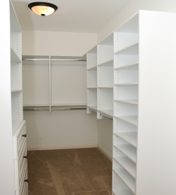 Empty clothes closet with white shelving and a ceiling light fixture, illustrating the importance of proper lighting for visibility and safety in closet spaces.