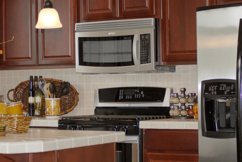 Modern kitchen appliances including a microwave, gas stove, and refrigerator, showcasing a functional kitchen environment relevant for discussions on appliance electrical issues.