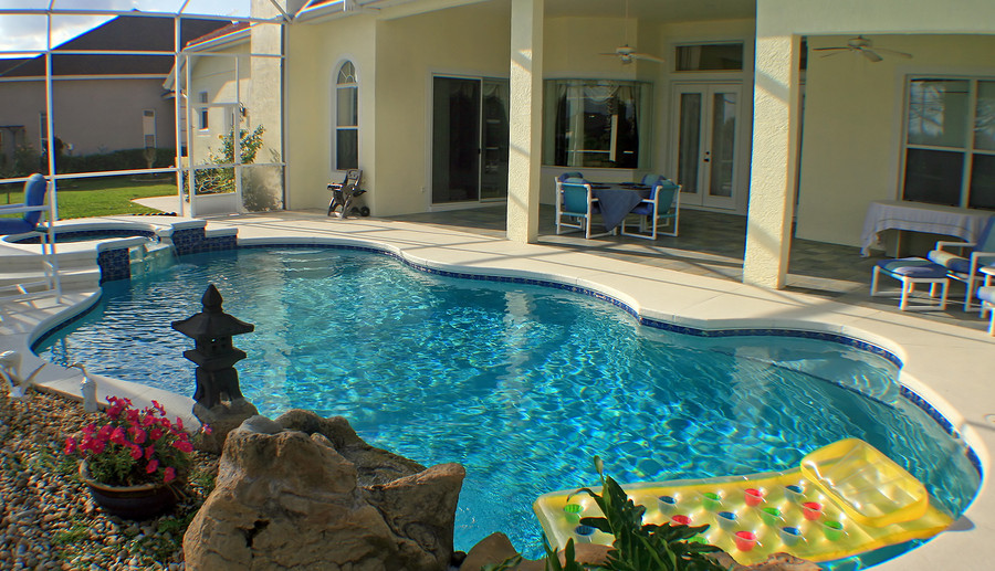 Swimming pool with clear blue water, surrounded by a patio, decorative rocks, flowers, and a floating lounge, emphasizing safety and relaxation in outdoor spaces.