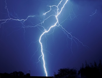 Lightning striking during a storm, illustrating the cause of electrical surges that can damage home appliances.